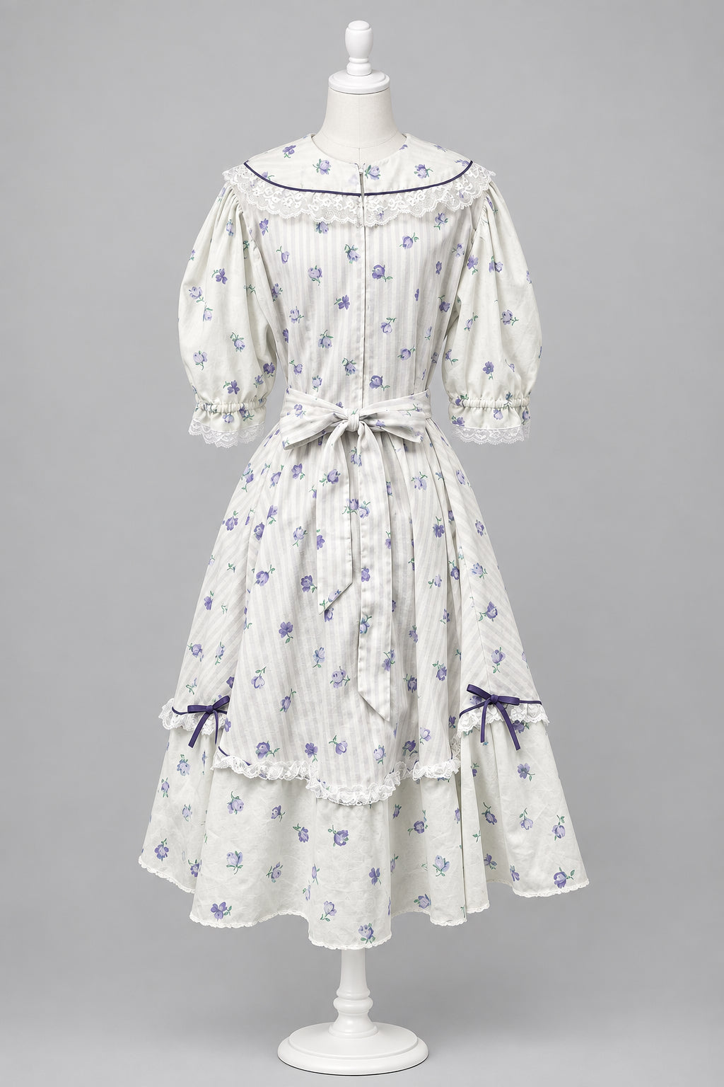 A white Victorian-style Lolita dress with Lavender floral prints and lavender stripes dark purple trim, displayed on a mannequin in studio