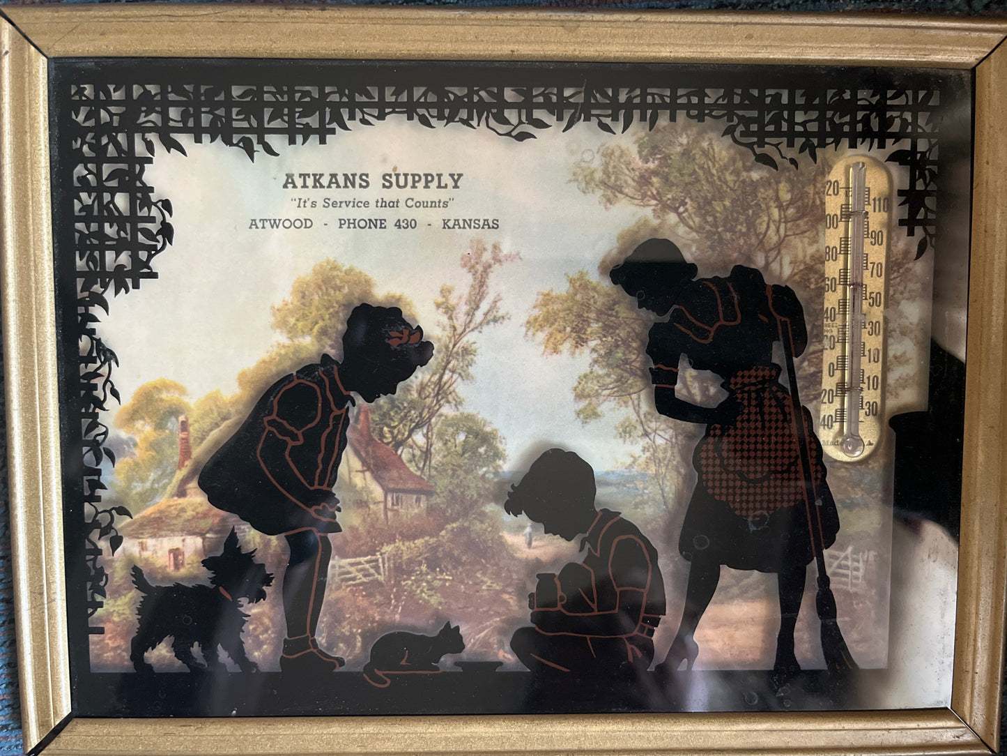 Framed artwork with silhouettes of people and animals, featuring the brand 'Atkans Supply'.