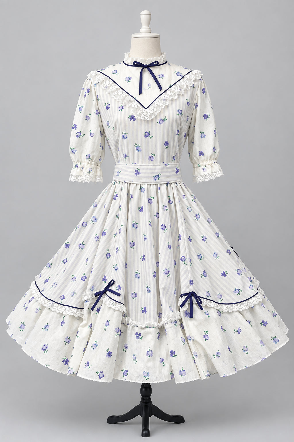 A white Victorian-style Lolita dress with Lavender floral prints and dark purple trim, displayed on a mannequin in studio