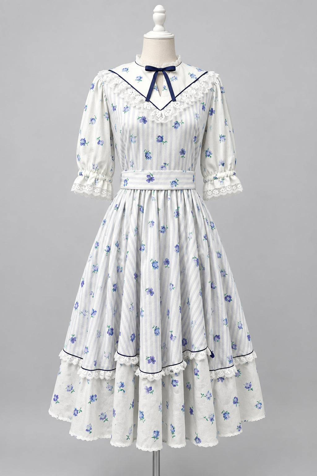 A white Victorian-style Lolita dress with Lavender floral prints and lavender stripes dark purple trim, displayed on a mannequin in studio