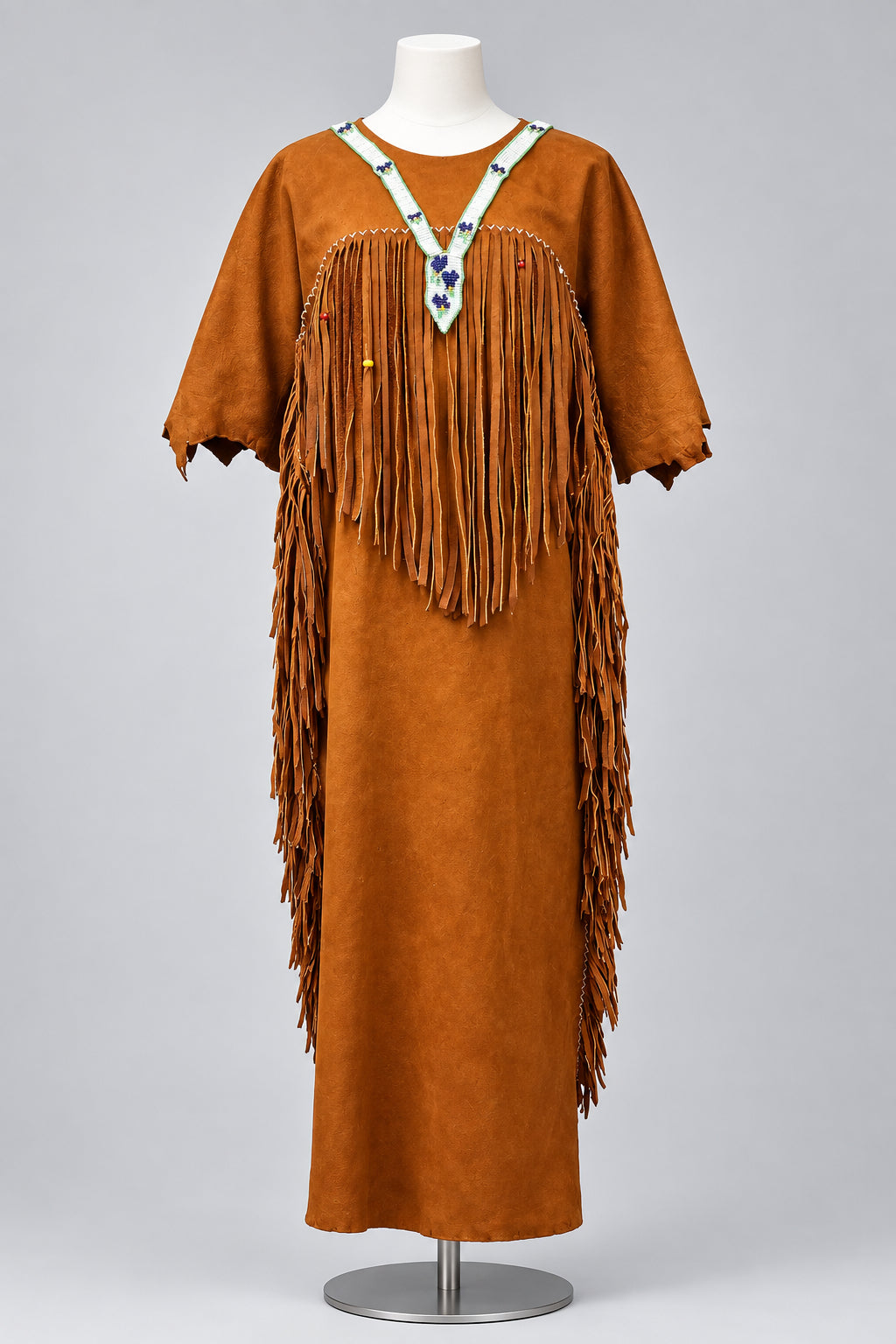 A rust-orange leather fringed dress displayed on a mannequin . The dress features a V-neckline with a decorative white and blue beaded collar and long fringe cascading down 